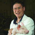 Dr. Maximus, standing with his pet micro-pig
